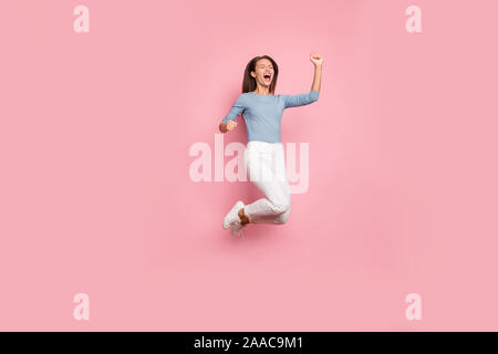 Toute la longueur de la taille du corps tourné photo de joie joyeuse fille excité fou de joie d'exprimer les émotions sur le visage de saut en pantalon pastel isolés Banque D'Images