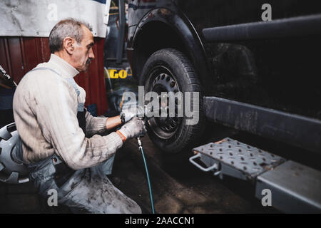 Bucarest, Roumanie - 21 novembre 2019 : faible profondeur de champ (selective focus) de droit avec un mécanicien de changer les pneus d'été d'une voiture avec Banque D'Images