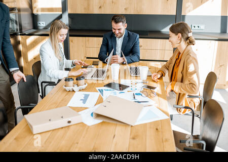 Les personnes qui travaillent avec des ordinateurs et des statistiques à l'imprimé table en bois dans la salle de réunion Banque D'Images