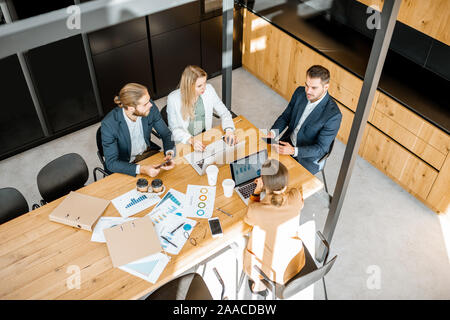 Les gens d'affaires travailler avec les ordinateurs et les statistiques au tableau en bois dans la salle de réunion, voir ci-dessus de la Banque D'Images
