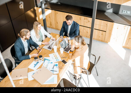 Les gens d'affaires travailler avec les ordinateurs et les statistiques au tableau en bois dans la salle de réunion, voir ci-dessus de la Banque D'Images