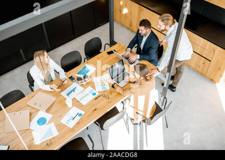 Les gens d'affaires travailler avec les ordinateurs et les statistiques au tableau en bois dans la salle de réunion, voir ci-dessus de la Banque D'Images