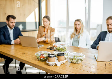 Les employés de bureau assis dans le bureau avec des repas d'affaires sur l'avant-plan. Concept de la nourriture à emporter en bonne santé sur les travaux Banque D'Images