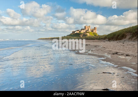 Château de Bamburgh haut perchées sur des rochers escarpés surplombant les dunes côtières, de la plage et de la mer du Nord. Northumberland, Angleterre Banque D'Images