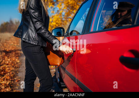 Voiture d'ouverture de porte. Femme ouvre voiture rouge avec la clé sur la route de l'automne. Prêt à partir du pilote Banque D'Images