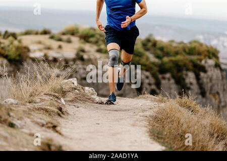 Blessure au genou sportif runner run dans les genouillères sur sentier de montagne Banque D'Images