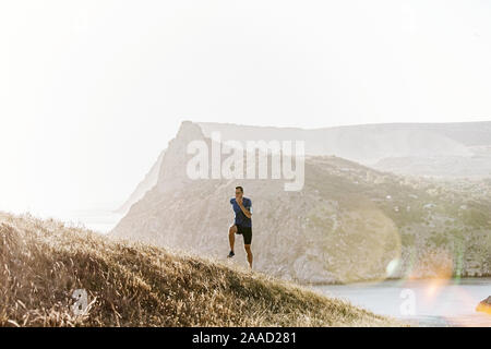 Coureur mâle avec des lunettes de soleil dans la montée d'exécution mer baie Banque D'Images