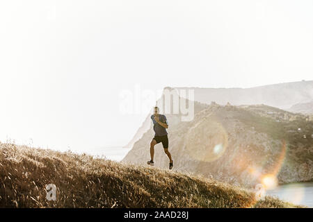 En marche vers l'homme avec des lunettes de soleil en runner, brassard titulaire cas téléphone Banque D'Images