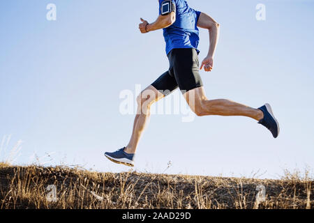 Homme runner sous mountain trail sur fond de ciel bleu Banque D'Images