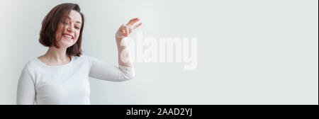 Happy girl smiling. Portrait of happy young woman laughing brunette positif montrant quelque chose dans la main copyspace isolé sur fond blanc. Femme européenne. L'émotion positive Banque D'Images