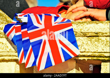 Mans hand on woman's hand holding Union Jacks à l'occasion d'un service Banque D'Images