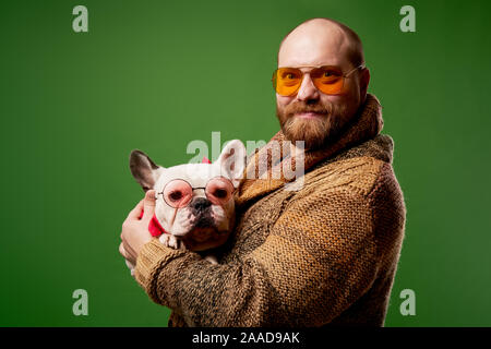 Homme avec bouledogue français dans ses bras sur fond vert vide Banque D'Images