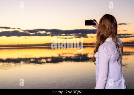 Jeune fille au coucher du soleil en prenant un smartphone selfies avec elle, la visite de l'Albufera de Valence, une réserve naturelle du lac. Banque D'Images