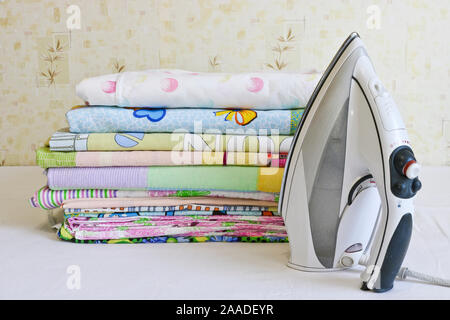 Fer à repasser moderne et pile de linge repassé. Les tâches ménagères. Banque D'Images