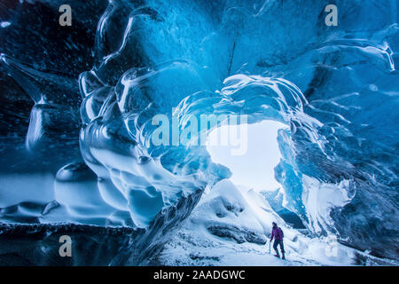 Femme marche dans une grotte de glace sous le glacier Breidamerkurjokull, l'Est de l'Islande. Février 2015. Parution du modèle. Banque D'Images