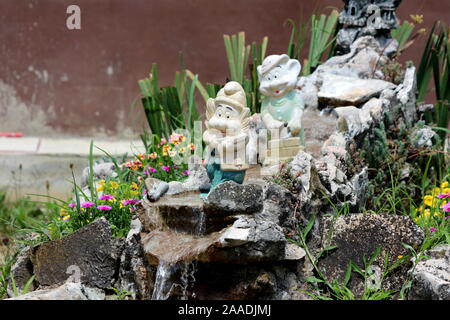 Les nains de jardin décoratif avec décolorées debout sur des cascades improvisées dans la banlieue de la maison de famille entourée de cour avant avec petit Banque D'Images