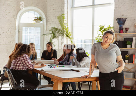 Les droits des femmes et l'égalité à l'office. Les jeunes femmes de race blanche ou confiant ennuyés en face de collègues ayant des problèmes de la réunion de travail, à la pression d'hommes et de harcèlement. Banque D'Images