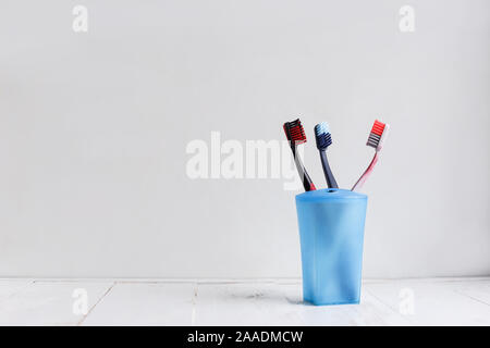 Brosses à dents de la famille en bleu tasse sur étagère en bois blanc Banque D'Images