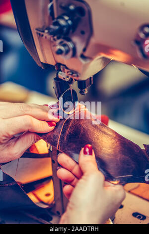 Cordonnier couture femme mains une partie de la chaussure lors d'un atelier. Processus de fabrication de chaussures en cuir, dans l'industrie de la chaussure à la main. Selective focus Banque D'Images