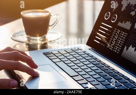 Personne travaillant sur ordinateur portable avec l'analyse commerciale et financière des données de rapport avec des mesures et des graphiques à l'écran au milieu de bureau moderne avec Banque D'Images