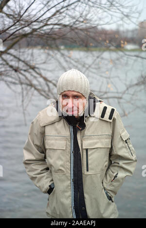 Un homme recroquevillé à froid, ce qui pose à l'extérieur, tir vertical Banque D'Images