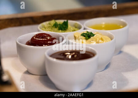 Des petits bols de différentes sauces sur un plateau dans un restaurant Banque D'Images