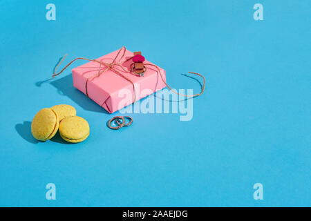 Macarons à anneau jaune sur fond bleu. La proposition de mariage, boîte cadeau rose et l'anneau. Copy space Banque D'Images