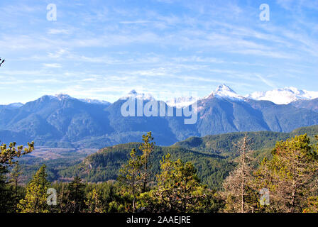 Une vue sur les montagnes de Tantalus avec un brillant ciel bleu et blanc, vert des conifères (sapins et pins), vu à Squamish randonnée Banque D'Images