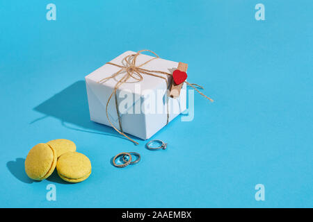 Macarons à anneau jaune sur fond bleu. La proposition de mariage blanc, boîte-cadeau et l'anneau. Copy space Banque D'Images