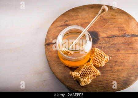 Le miel et le balancier dans un bocal en verre sur un sol en bois Banque D'Images