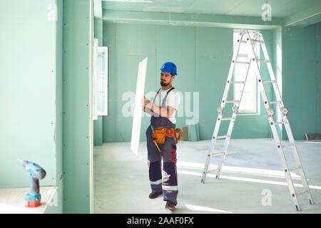 Constructeur travailleur installe des cloisons sèches à une construction de plâtre Banque D'Images