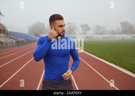 Guy Sports avec une barbe debout dans le stade le matin dans le brouillard. Banque D'Images