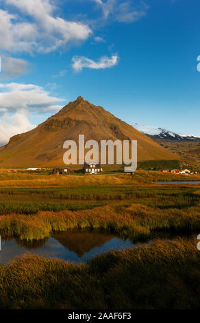 À Arnarstapi matin reflétant dans l'eau Mt. Stapafell en forme de pyramide et Amtmannshusid palagonite mountain house avec glacier Snaefellsjokull dans b Banque D'Images