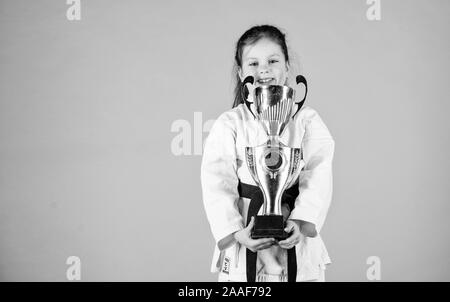 L'énergie et de l'activité. pour les enfants. winner petite fille dans gi sportswear. Petite fille avec champion cup. art martial pratiquer Kung Fu. enfance heureuse. sport succès en combat singulier. copier l'espace. Banque D'Images