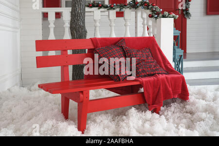 Couverture et coussins rouges sur banc rouge avec blanc neige artificielle piscine Banque D'Images