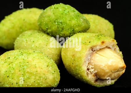 Arachides enrobées de wasabi sur ardoise. Wasabi japonais d'épices. Wasabi vert arachides sur une plaque noire sur un fond sombre. Banque D'Images