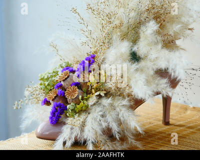 Arrangement de fleurs séchées dans une chaussure avec l'herbe de la pampa à l'aide de chaussures de mariage et fleurs séchées comme souvenir Banque D'Images