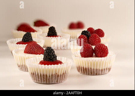 Des gâteaux faits maison et sauce aux fraises accompagné de fraises, mûres et framboises sur fond blanc. Banque D'Images