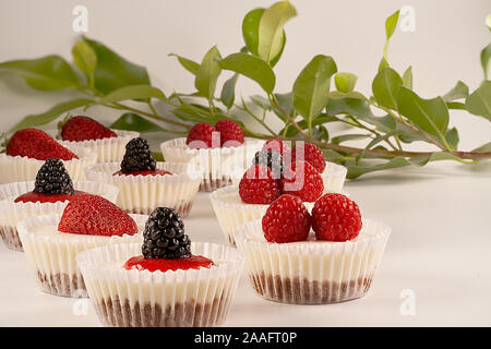 Des gâteaux faits maison et sauce aux fraises accompagné de fraises, mûres et framboises sur fond blanc. Banque D'Images