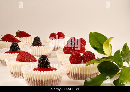 Des gâteaux faits maison et sauce aux fraises accompagné de fraises, mûres et framboises sur fond blanc. Banque D'Images