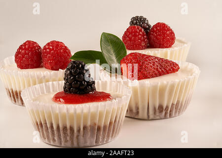 Des gâteaux faits maison et sauce aux fraises accompagné de fraises, mûres et framboises sur fond blanc. Banque D'Images