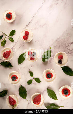 Des gâteaux faits maison et sauce aux fraises accompagné de fraises, mûres et framboises sur fond blanc. Banque D'Images