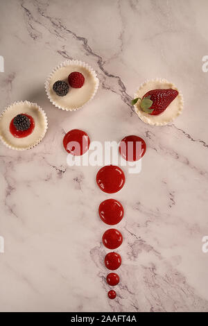 Des gâteaux faits maison et sauce aux fraises accompagné de fraises, mûres et framboises sur fond blanc. Banque D'Images