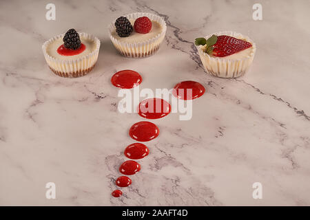 Des gâteaux faits maison et sauce aux fraises accompagné de fraises, mûres et framboises sur fond blanc. Banque D'Images