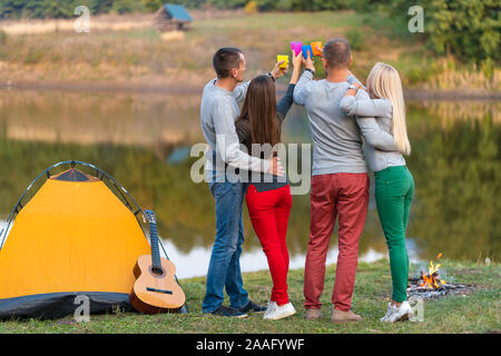 Pique-nique avec des amis au lac près de la tente de camping. Les amis de l'entreprise avoir pique-nique Randonnée nature background. Les randonneurs se détendre pendant le temps de boire. Summer picn Banque D'Images