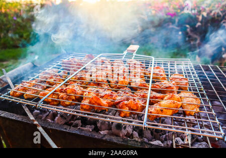 Cuire les brochettes de poulet sur le barbecue dans le jardin au coucher du soleil Banque D'Images
