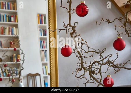 Close up of red christmas balls dans une succursale en face d'un mur blanc et un miroir avec cadre doré avec des reflets d'un loft Banque D'Images