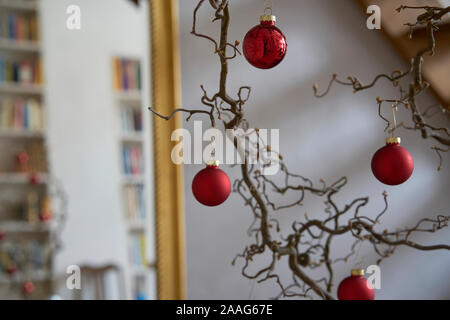 Close up of red christmas balls dans une succursale en face d'un mur blanc et un miroir avec cadre doré avec des reflets d'un loft Banque D'Images