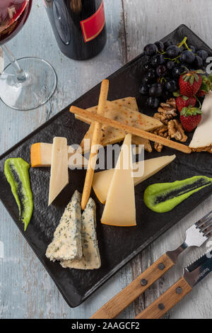 Assiette de fromage servi avec des raisins, des fraises, des craquelins et des écrous sur un fond de bois Banque D'Images