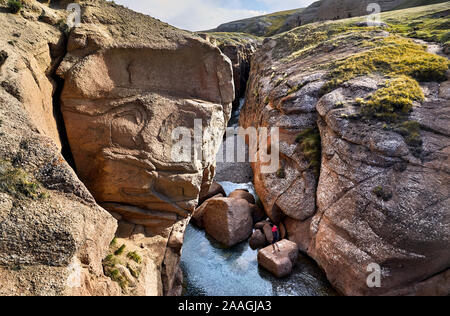 Petit homme sur le rocher dans le canyon avec river dans la région de Naryn, Kirghizistan Banque D'Images